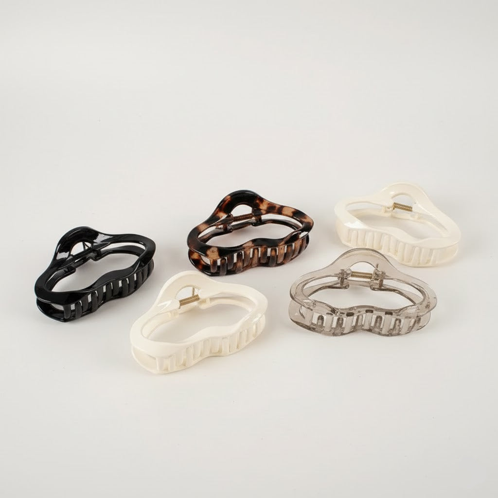 Set of five hair clips in black, tortoiseshell, white, and clear on a light gray background
