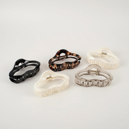 Set of five hair clips in black, tortoiseshell, white, and clear on a light gray background
